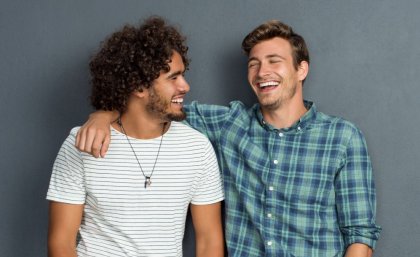 Two young men smile and joke together as friends.